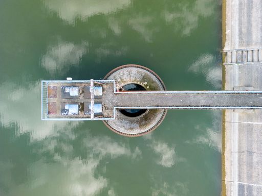 Aerial drone view of a concrete hydroelectric dam with a pump station situated on a serene lake