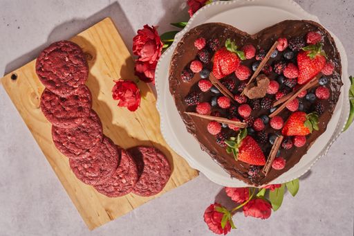 An overhead shot of a heart-shaped brownie cake and red velvet cookies with roses to celebrate mother's day