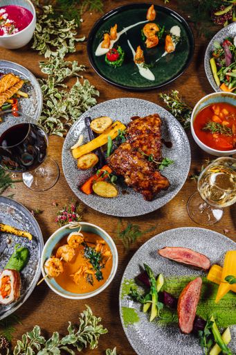 A vertical shot of a variety of dishes on a wooden table decorated with plants
