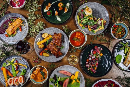 A variety of dishes on a wooden table decorated with plants