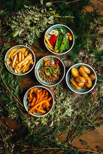 A vertical shot of a variety of dishes on a wooden table decorated with plants