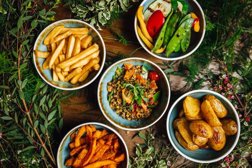 A variety of dishes on a wooden table decorated with plants