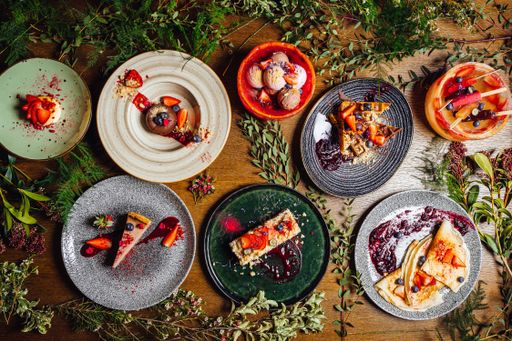 A variety of dishes on a wooden table decorated with plants