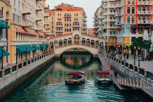 The boats float underneath a bridge on the breathtaking Pearl of Qatar Island in the city of Doha, Qatar