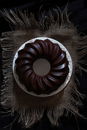 A vertical top view of a gourmet chocolate bundt cake on a dark table
