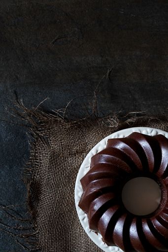 A vertical top view of a gourmet chocolate bundt cake on a dark table