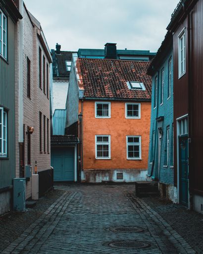 A vertical shot of a narrow empty street surrounded by colorful buildings