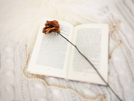 A closeup shot of an open book with beads and a beautiful dried flower