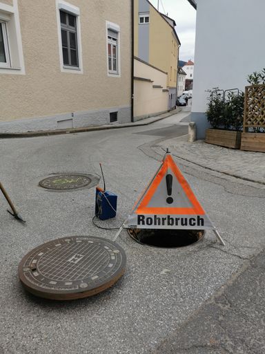 A danger sign saying "broken pipe" in german on the street