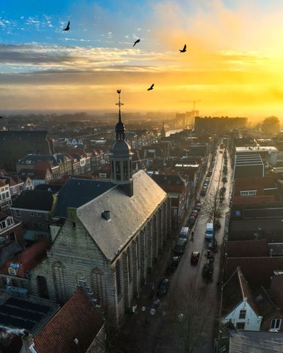 A stunning urban landscape of the Kapelkerk and Alkmaar skyline at dusk with birds