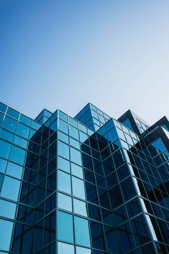 A high-rise glass office building with a modern design, illuminated by the afternoon sun