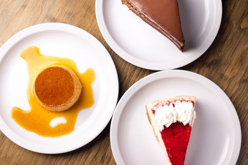 A top view of dessert cakes served in white plates on a wooden surface