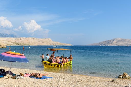 Boat carrying tourists on excursion around beautiful Pag island in adriatic sea in Croatia. Boat anchored near Beritnica beach.