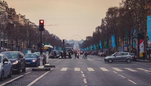 A shot of a busy street with crosswalks, cars, and traffic lights in Paris, France