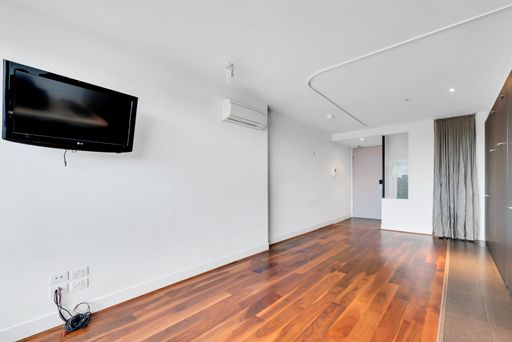 An unfurnished living room with a TV on a wall and laminate flooring