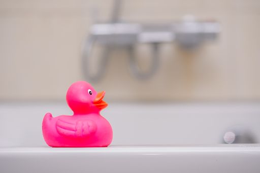 A closeup shot of a pink duck toy in the bathroom