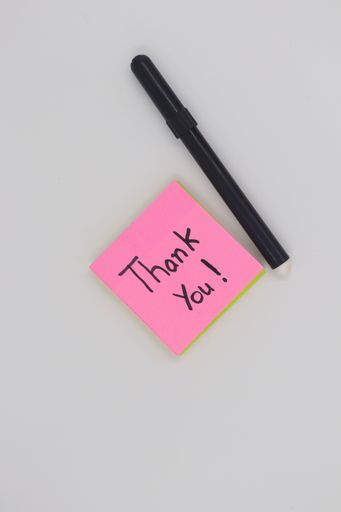 A pink notepad and pen, featuring the words "Thank You" written on the paper