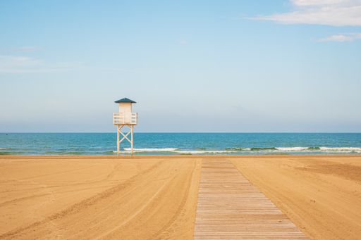 A natural of a lifeguard house on a sandy beach against a clear blue sky