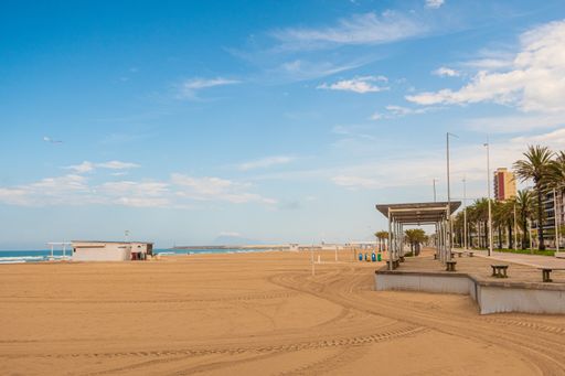 A scenic view of an empty sandy beach under a wispy sky