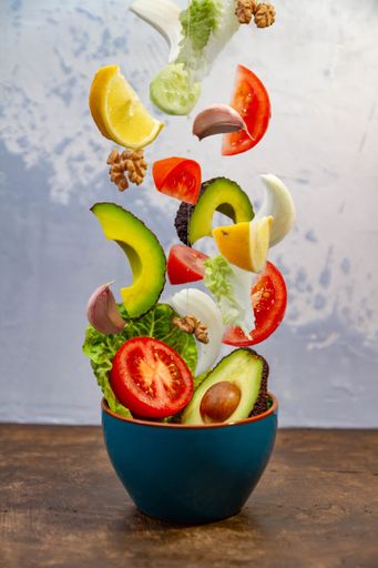 A vertical shot of jumping fruits and vegetables from a blue pot