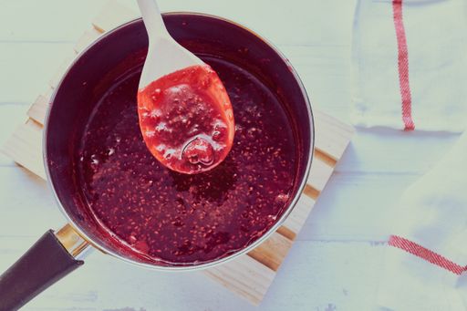 A high angle view of raspberry jam in a pot on the table under the lights