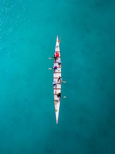 An aerial top view of a sailboat in a turquoise sea