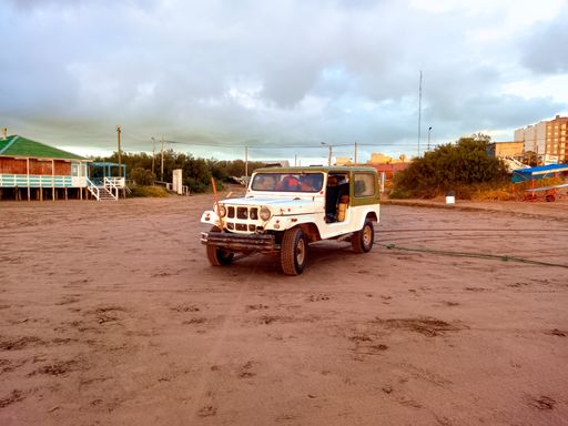 An old off road ramshackle jeep in the sand of the beach