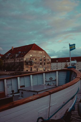 A vertical shot of a white boat in the harbor in Copenhagen, Denmark during sunset