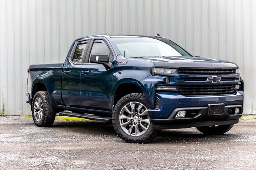 A blue Chevrolet Silverado pickup truck parked in a lush green grassy field.