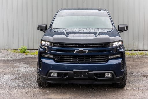 A blue Chevrolet Silverado pickup truck parked in a lush green grassy field.