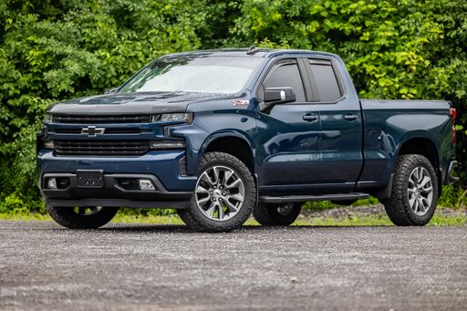 A blue Chevrolet Silverado pickup truck parked in a lush green grassy field.