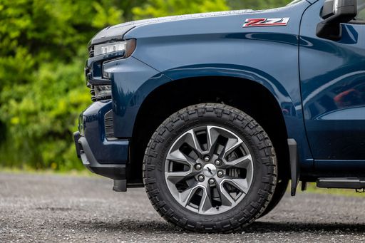 A blue Chevrolet Silverado pickup truck parked in a lush green grassy field.