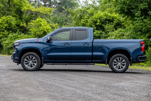 A blue Chevrolet Silverado pickup truck parked in a lush green grassy field.