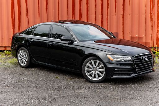 A black Audi car parked in front of a red garage.