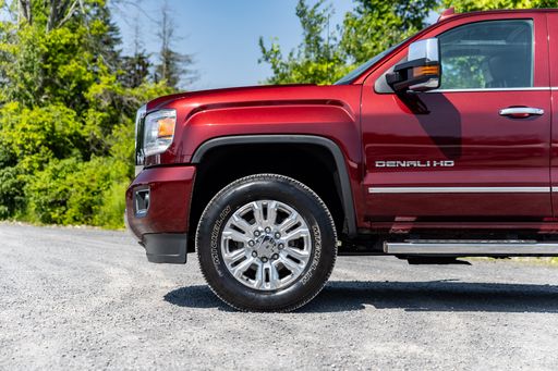 A red GMC pickup truck parked in a lush green grassy field.