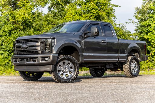 A black Ford pickup truck parked in a lush green grassy field.