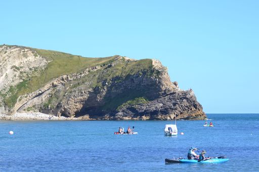 A beautiful landscape of Lulworth Cove in Dorset, England with boats in the foreground