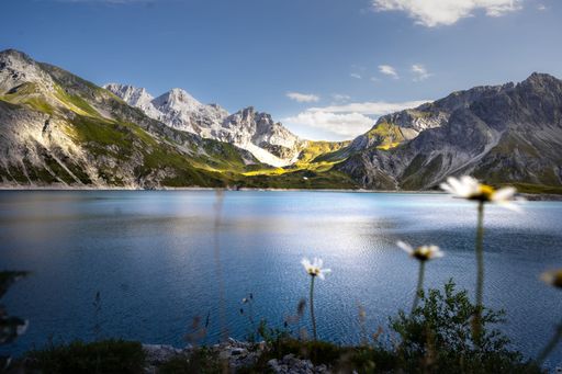 The tranquil Lunersee lake surrounded by lush green grass and jagged mountains in Austria