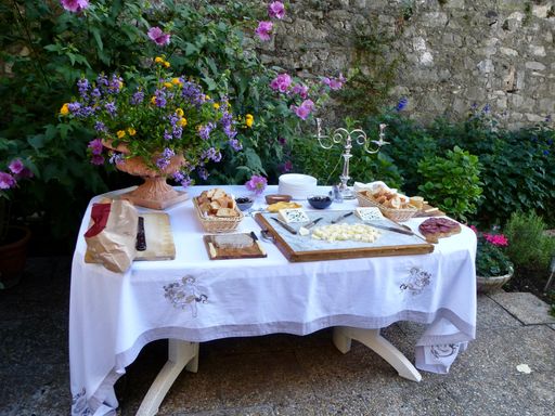 An outdoor dining table with a variety of food, drinks and vases of flowers, all ready for a meal