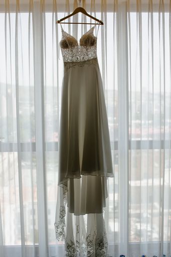 A vertical of a wedding dress on a hanger against a window