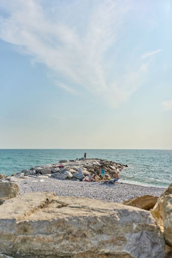 A scenic shot of a rocky beach with a pier extending out into the ocean