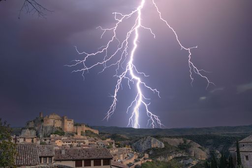 Spectacular storm in the medieval village of Alquezar. In the background, an impressive lightning and to the left is the walled village