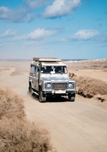 A vertical shot of an off-road car moving in a desert road