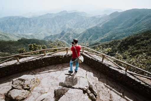 A man taking photos of beautiful mountain range from a view deck