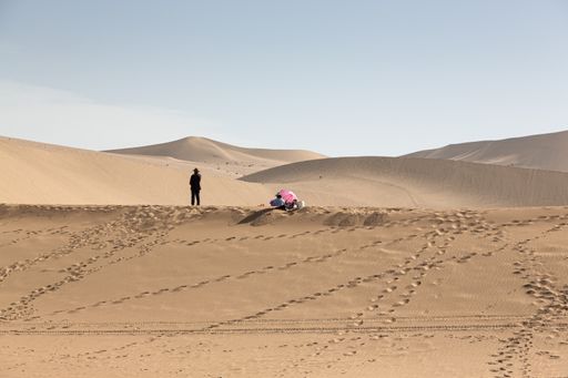 The two people in a desolate desert landscape against the background of dunes. Kumtag Desert, China
