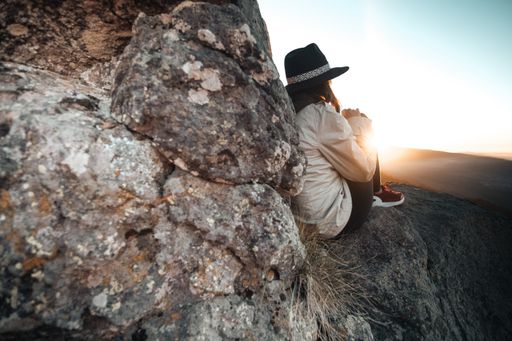 A woman witting at the edge of a rock with a beautiful view of the sunrise