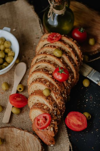 A vertical shot of delicious bread, tomatoes, and olives on a rustic background