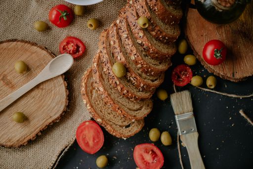A top view of delicious bread, tomatoes, and olives on a rustic background