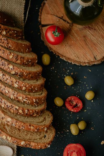 A vertical shot of delicious bread, tomatoes, and olives on a rustic background