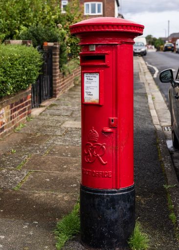 A Red Royal Mail post box by the road side